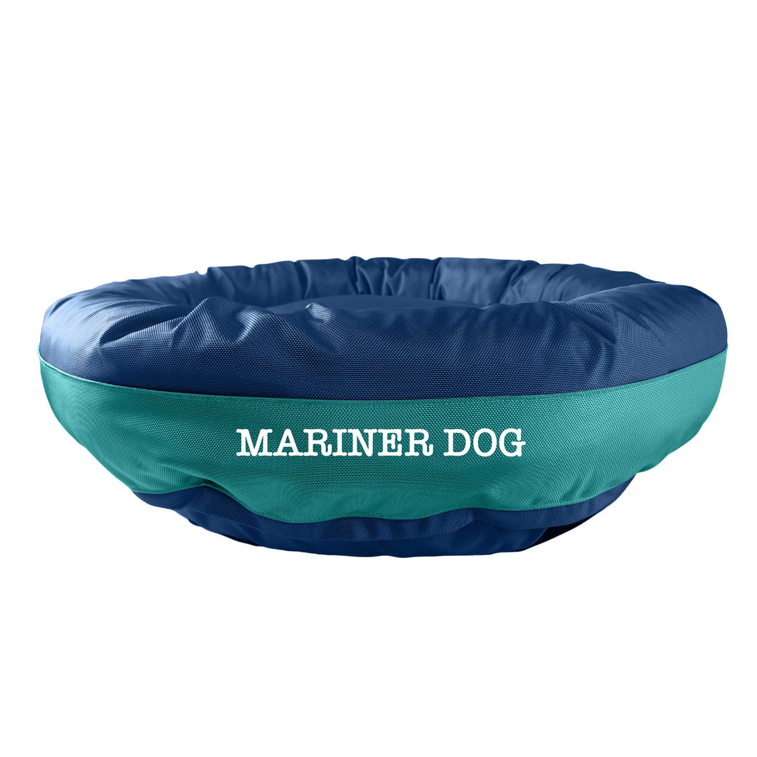 Navy round bolstered dog bed with a teal band and white embroidered 'Mariner Dog'.  Edit alt text