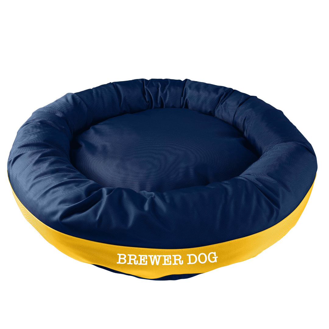 Navy round bolstered dog bed with yellow band in the middle with white embroidered "Brewer Dog'.