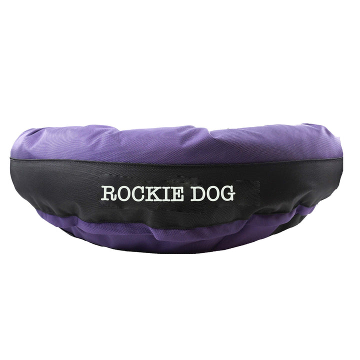 Purple round bolstered dog bed with a black band and white embroidered "Rockie Dog'.