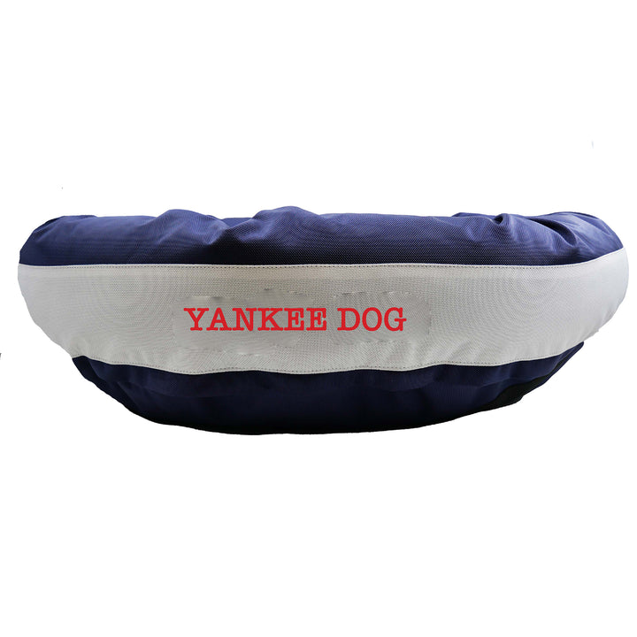 Navy round bolstered dog bed with a silver band and red embroidered 'Yankee Dog'.