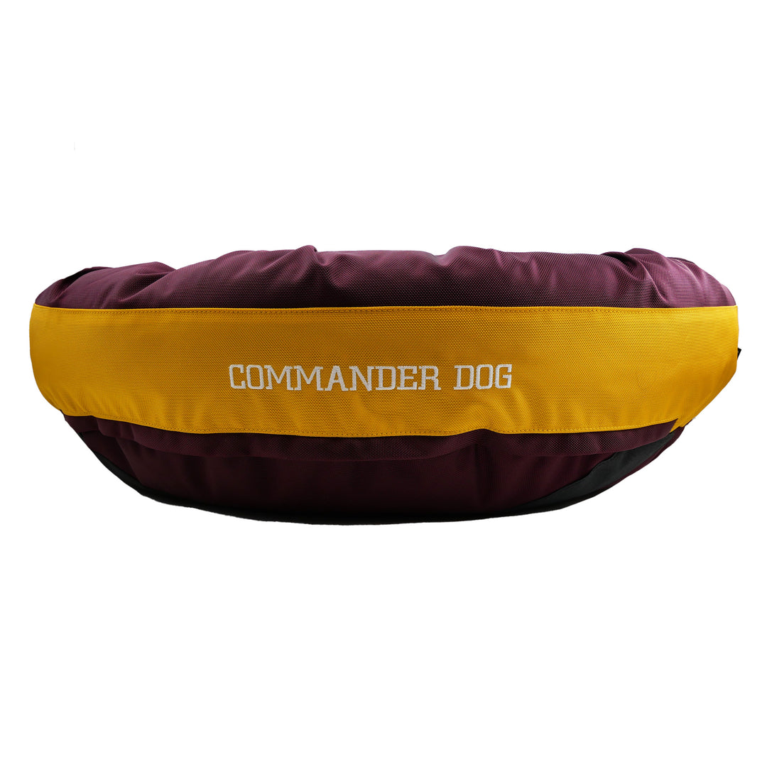 Maroon and gold round bolstered dog bed with Commander Dog embroidered in white