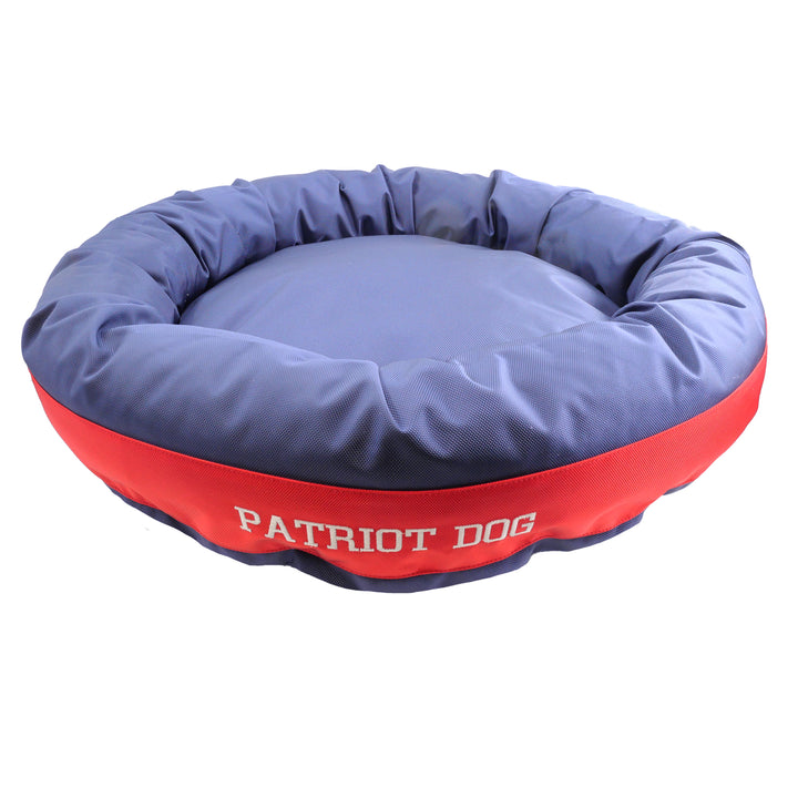 Blue and red round bolstered dog bed with embroidered 'patriot dog'